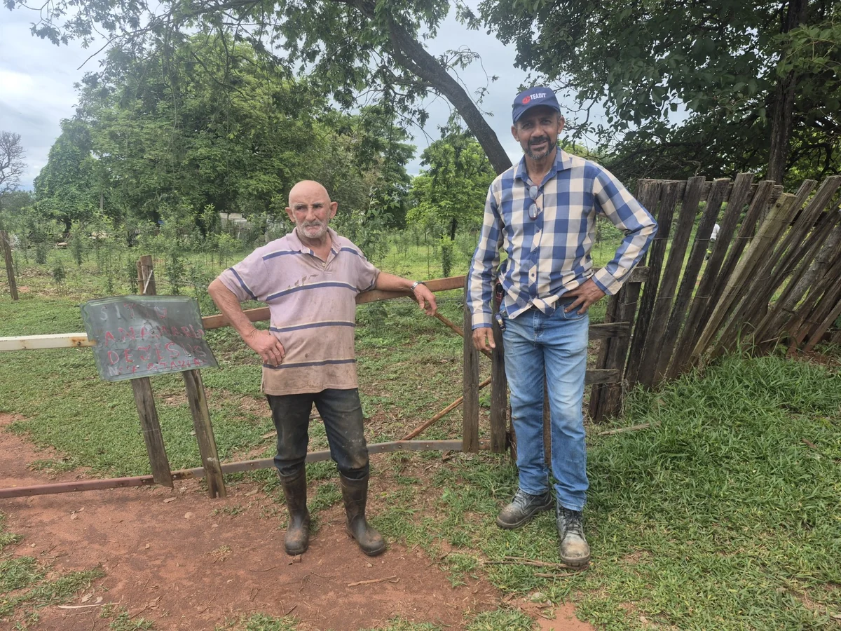 Famílias sem energia em Castilho: “sofrimento não pode ser normalizado”, diz advogado Dois homens em frente à porteira e cerca de madeira de uma propriedade rural