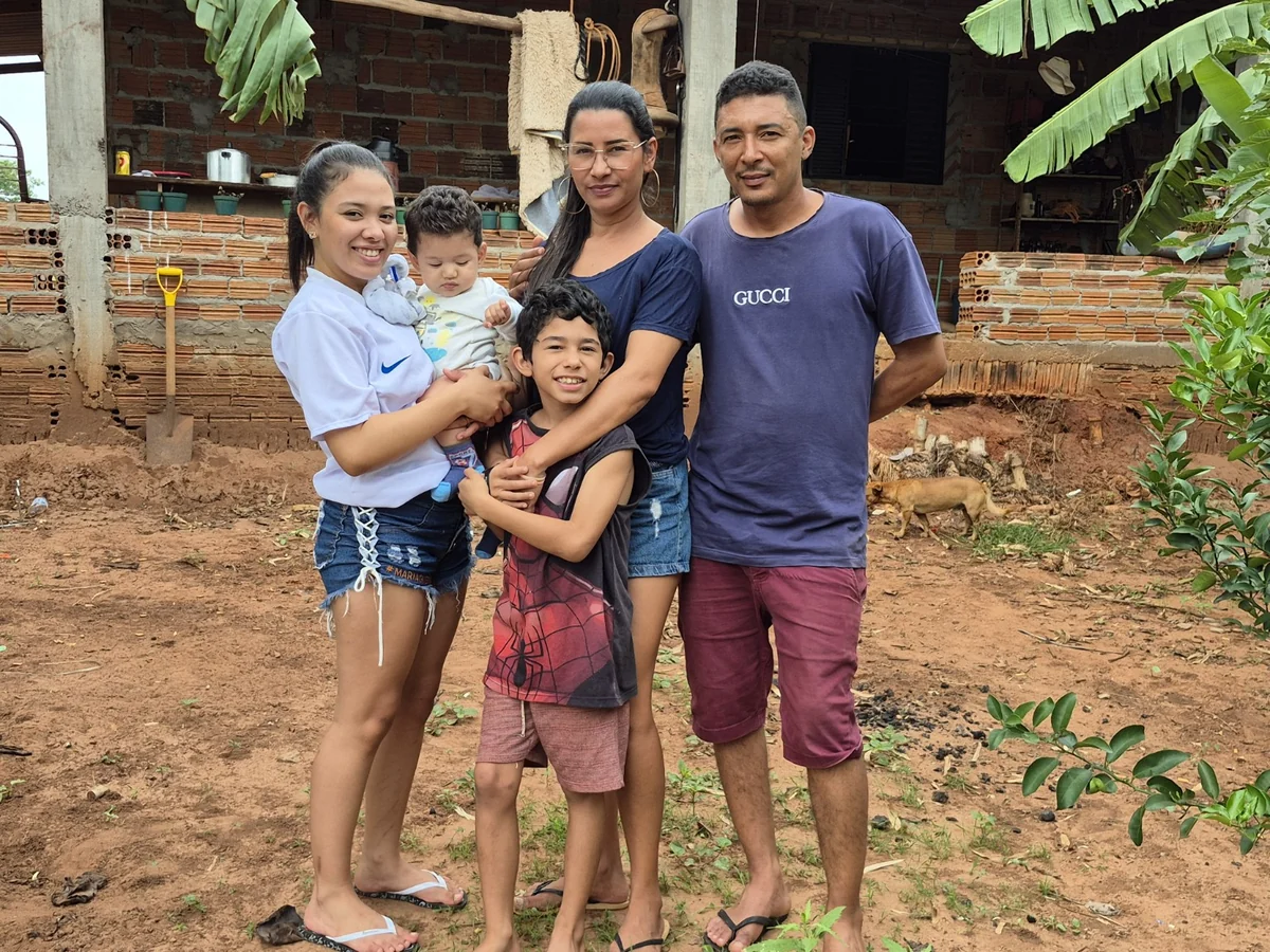 Famílias sem energia em Castilho: “sofrimento não pode ser normalizado”, diz advogado Adultos e crianças reunidos diante de uma casa de tijolos aparentes em área rural