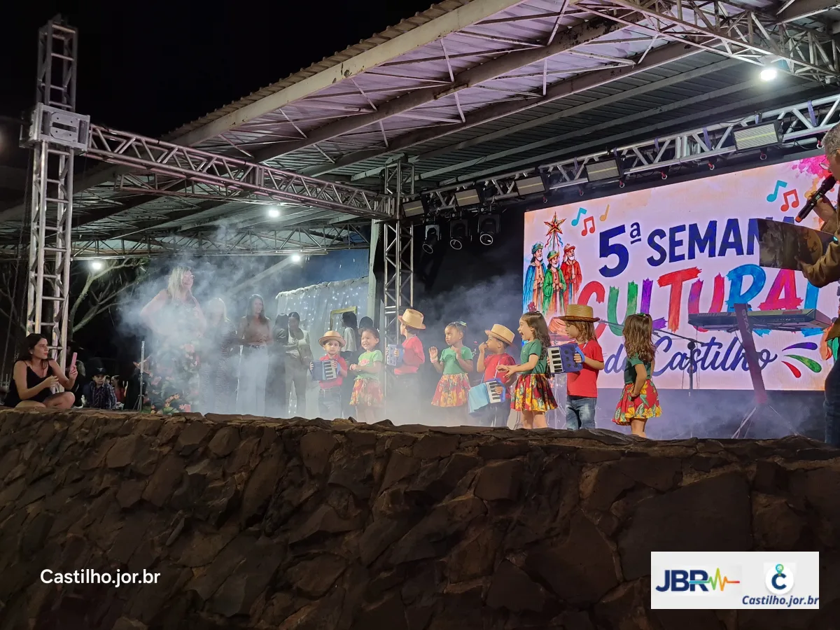 Crianças se apresentam no palco com figurinos coloridos e efeitos de fumaça