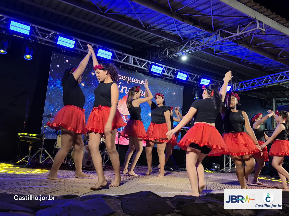 Bailarinas com saias vermelhas se apresentam sob iluminação azul