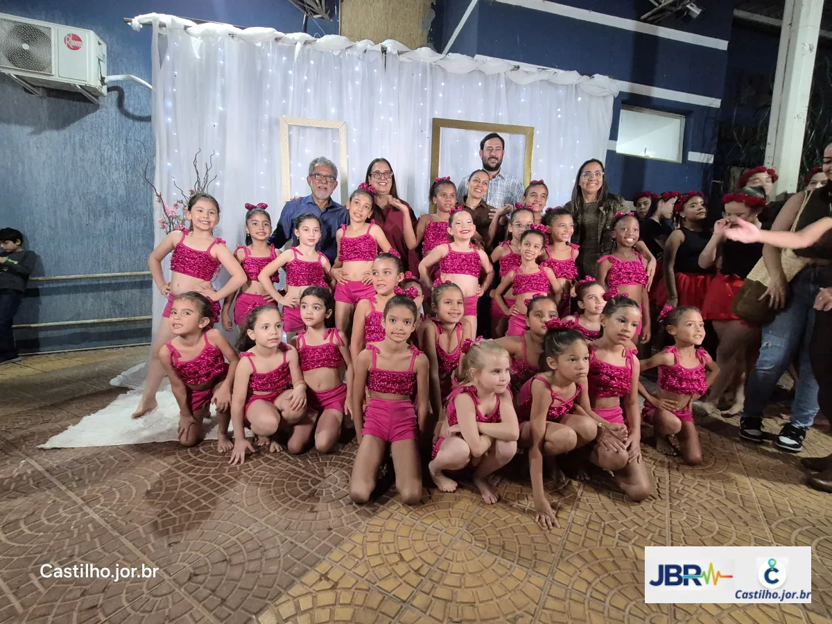 Grupo de crianças com figurinos de dança e adultos reunidos para foto no evento